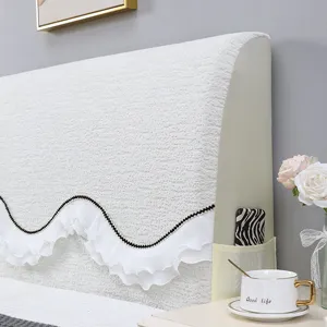 White textured headboard cover with elegant lace ruffle and side storage pocket detail.