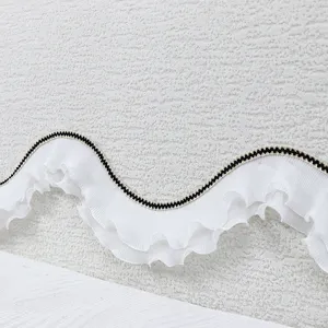 Close-up detail of white pleated headboard cover with elegant ruffle trim texture.