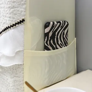 Soft beige bedside headboard cover detail showing side pocket, plush texture and pleated trim.