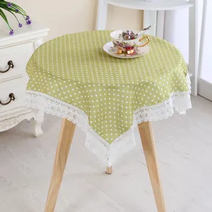 Green polka dot tablecloth detail with white lace trim, fresh style table cover for home decor.