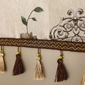 Vista detallada de la elegante tela de cubierta antipolvo decorada con fino bordado y borlas.