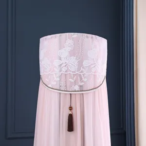 Dettaglio di copri condizionatore verticale in pizzo rosa con ricamo floreale e nappa elegante.