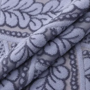 Close-up view of grey lace dust cover fabric featuring soft textured floral pattern detail.