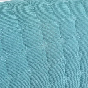 Close-up of teal quilted corduroy headboard cover fabric texture, soft and thick material.