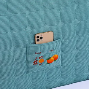 Thickened quilted headboard cover detail showing convenient phone pocket and cute orange embroidery.