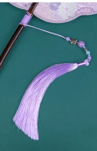Nahaufnahme des traditionellen chinesischen Fächergriffs mit lila Quaste und Perlen.