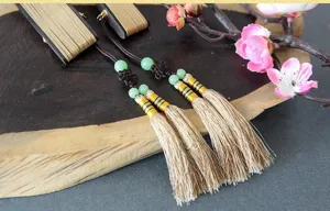 Close-up detail of Chinese style wooden fan pendant with delicate tassels and green beads.