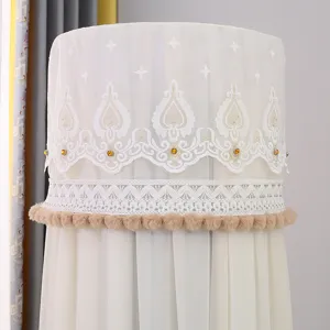 Dettaglio copri condizionatore cilindrico in pizzo beige con frange pon pon eleganti