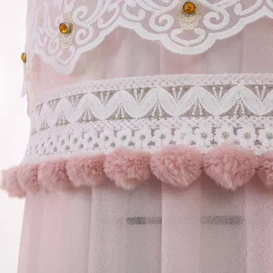 Vista dettagliata della copertura in pizzo rosa per condizionatore con pompon e strass.