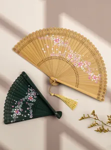 Close-up of traditional Chinese hollow carved bamboo folding fans with cherry blossom floral prints.