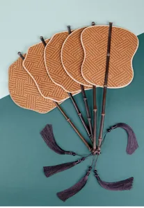 Traditional handmade woven bamboo fan with dark handle and tassel for daily summer cooling.