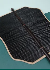 Closeup of traditional Chinese handheld fan detail, black bamboo slat and purple bamboo handle.