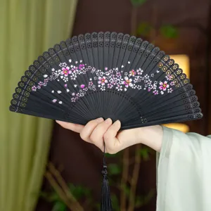 Black bamboo folding fan with delicate hollow carved ribs and pink cherry blossom art.
