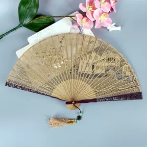 Traditional Chinese wooden hollow-carved folding fan with tassel, elegant retro gift fan.