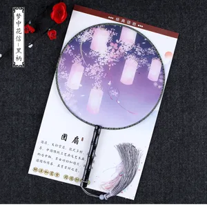 Traditional Chinese round fan detail, cherry blossom pattern, wooden handle and tassel.
