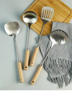 Stainless steel kitchen utensils set with wooden handle spatula ladle skimmer cooking tools detail.