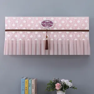 Copertura antipolvere per climatizzatore in pizzo rosa con nappa ed etichetta decorativa.