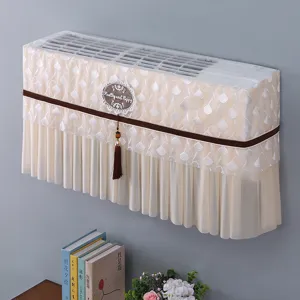Vista dettagliata della copertura per condizionatore in pizzo beige con nappina e targa.