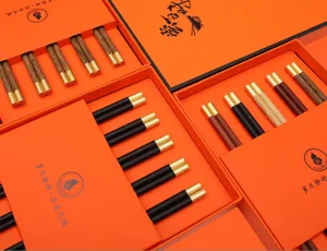 Detailed view of luxury wooden chopstick gift sets in elegant orange boxes with gold tips.