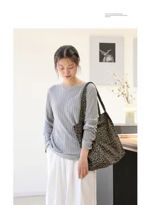 Vrouwelijk model draagt een retro canvas tas met luipaardprint in een lichte kamer