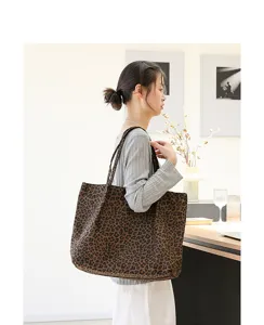 Aziatisch model met een canvas draagtas met panterprint in een minimalistisch interieur