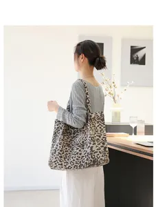 Detailweergave van retro canvas draagtas met luipaardprint gedragen door een model