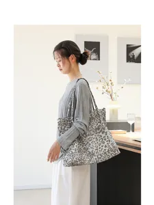 Model draagt een grote canvas draagtas met luipaardprint in een binnenomgeving