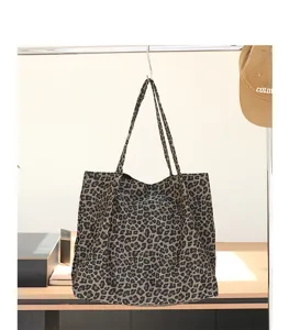 Detailopname van een canvas draagtas met luipaardprint hangend in een lifestyle setting.