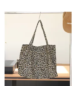 Casual canvas draagtas met luipaardprint hangend aan een kledingrek in een studiodecor