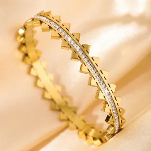 Gold titanium steel bangle featuring sparkling cubic zirconia and chic pyramid studs.