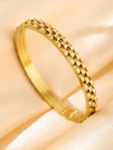 Golden stainless steel fluted bangle bracelet detail view, elegant textured metal cuff jewelry.