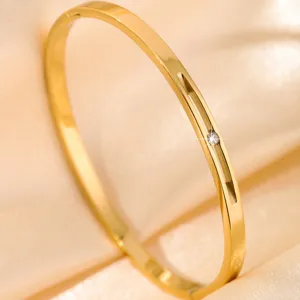 Gold titanium steel bangle detail featuring a delicate sparkling crystal and elegant slot design.