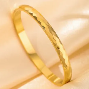 Golden hammered bangle detail showing exquisite textured surface and glossy metallic finish.