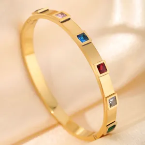 Detailed closeup of golden stainless steel bangle featuring colorful square crystal stones.