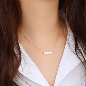 Elegant minimalist freshwater pearl necklace with gold bar pendant shown on model