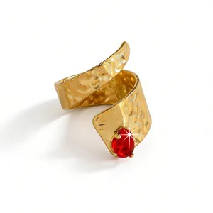 Close-up detail of a gold-tone hammered open ring featuring a sparkling red teardrop zircon stone.
