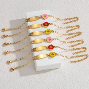 Detailansicht von goldenen Edelstahl Armbändern mit gravierbaren Schildchen und bunten Blumen.