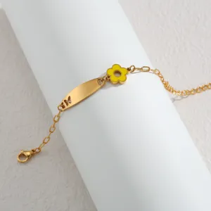 Nahaufnahme Detail des goldenen Edelstahl Armbands mit gelbem Emaillierter Blumenanhänger.