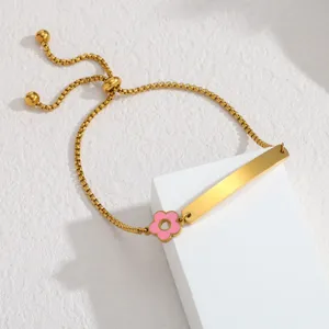 Edelstahl Gold verstellbares Armband mit gravierbarem Plättchen und rosafarbenem Blumenanhänger.