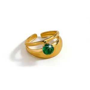 Close-up of a wide open gold-plated ring featuring a sparkling round green zircon stone.
