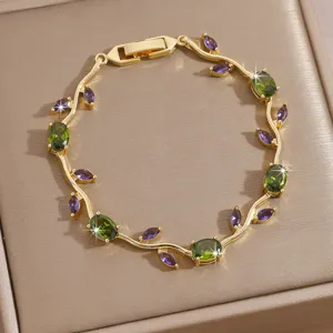 Detailed closeup of gold plated vine bracelet featuring green and purple cubic zirconia gemstones.