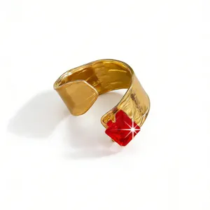 Detail shot of a wide open gold-plated ring featuring a bold square red gemstone accent.