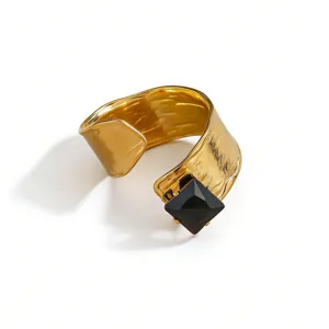 Wide gold-plated metal ring detailed with a striking square black cubic zirconia stone.