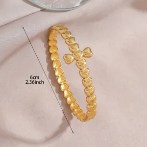 Gold-plated stainless steel open bracelet featuring heart links in a stylish cross design.