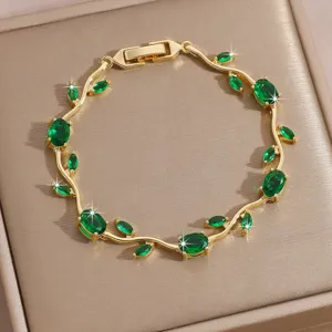 Close-up of elegant gold-tone vine bracelet sparkling with vibrant green cubic zirconia stones.