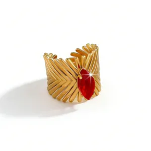 Close-up of a bold gold-plated stainless steel cuff ring featuring a striking marquise red stone.