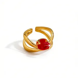 Detailed close-up of the gold-plated open ring with a sparkling red zirconia stone and split shank.