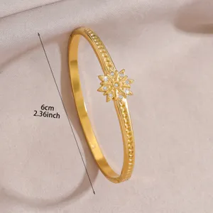 Gold metal bangle bracelet with sparkling crystal star motif and elegant luxury design detail.