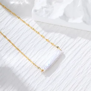 Close-up of minimalist gold chain necklace featuring a long white baroque pearl pendant