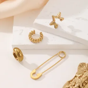 Gros plan détail de boucles d'oreilles étoile géométrique et épingle à nourrice en acier.